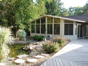 Modern sunroom exterior shot in front of backyard with pond